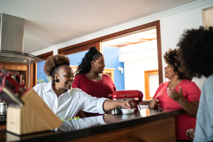 Friends or family reunited talking in the kitchen at home