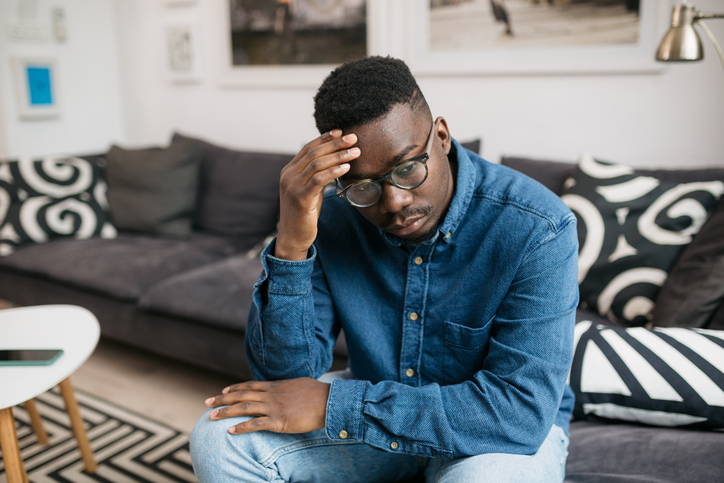 Young depressed African American man sitting at home