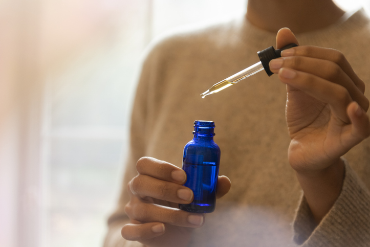 Woman's hand holding pipette and bottle of aromatherapy oil