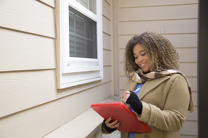 Lovely African American woman completes real estate appraisal for home sale.