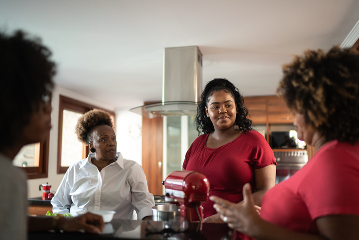 Friends or family reunited talking in the kitchen at home