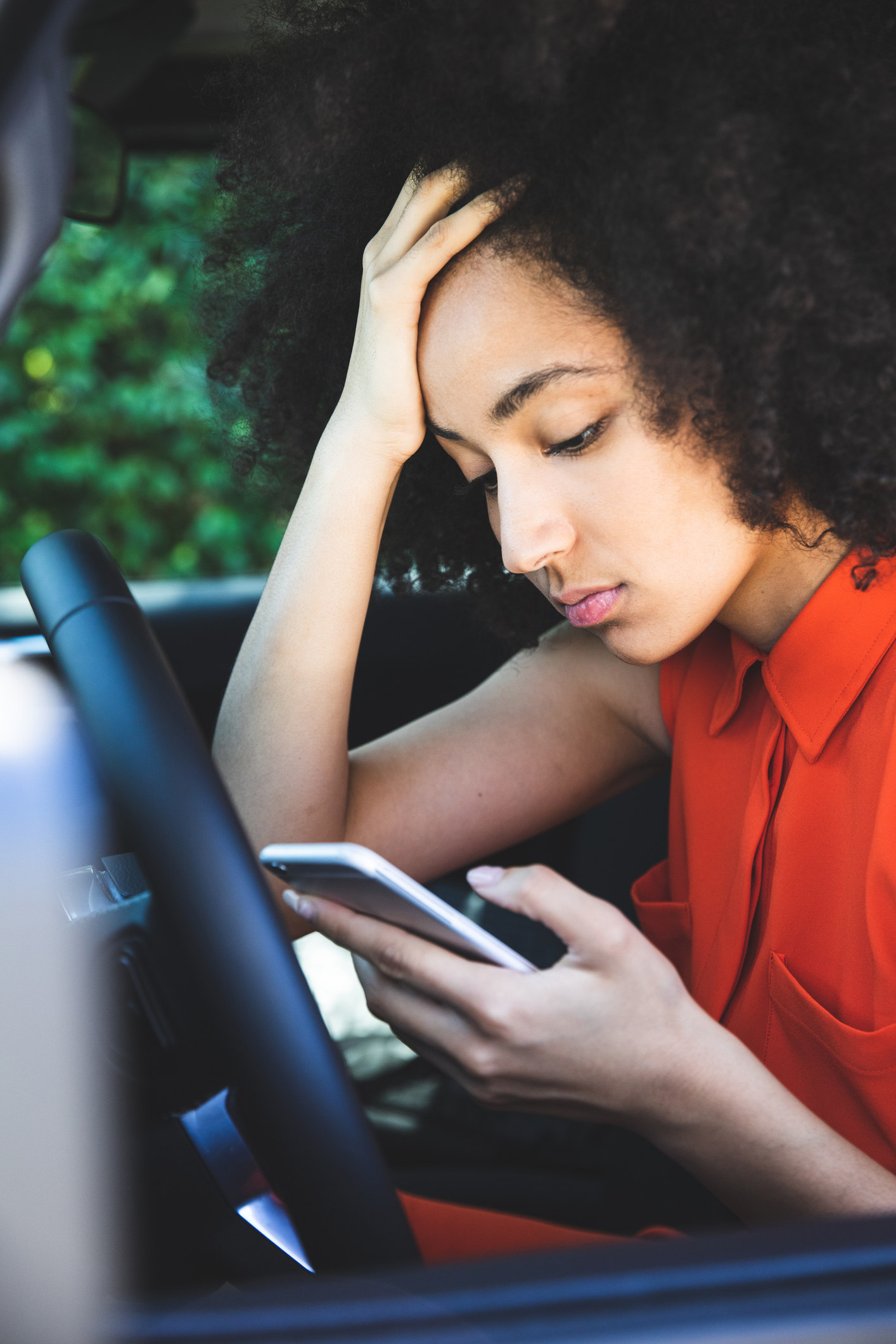 Woman waiting in the car and, annoyed, scrolling social media