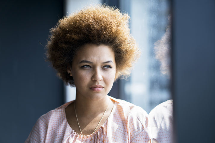 Thoughtful businesswoman leaning on glass wall