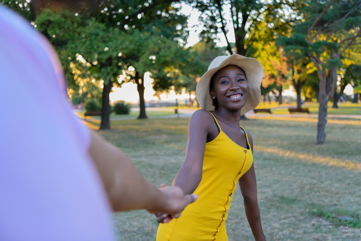 Cheerful African-American Couple is Walking in Public Park While Holding Hands.