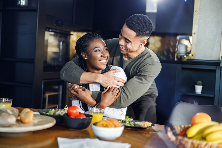 Embraced African American couple talking in dining room.