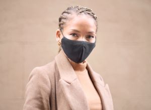 Headshot portrait of a young woman wearing a black protective face mask.