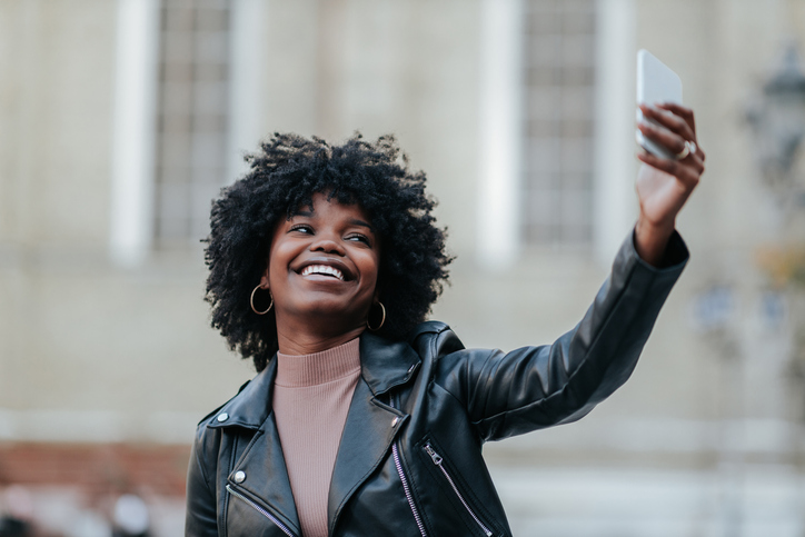 Smiling afro woman taking selfie while she is out in the city
