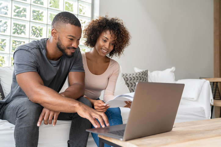 African American couple paying bills online at home