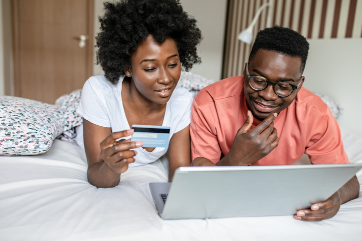 Portrait of African American couple in bed doing online shopping