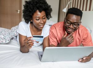 Portrait of African American couple in bed doing online shopping