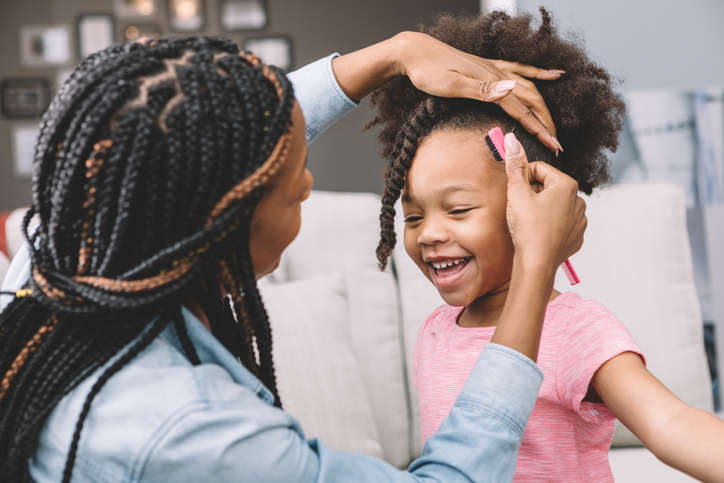 mother styling daughter's curly hair