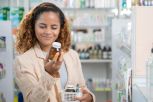 Young woman compares medicine labels in pharmacy.