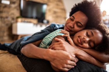 Mother and daughter sleeping together in the living room.