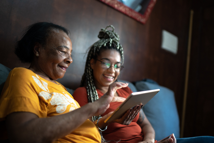 Grandmother and granddaughter doing a video conference on digital tablet at home