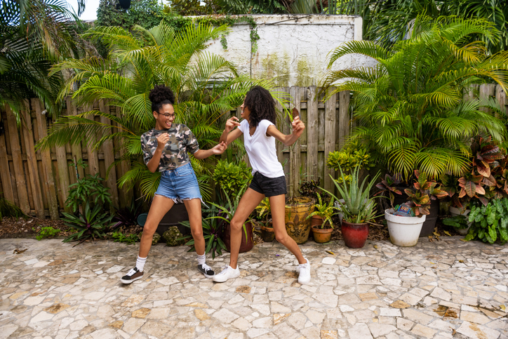 Two Teenage African American Sisters Dancing in the Backyard at Home in Miami