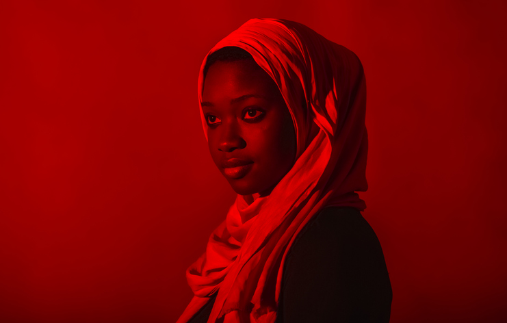 Woman wearing hijab looking away against red background