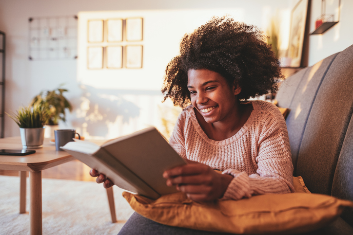 African student reading book at home