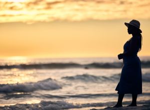 Shot of an unrecognizable woman walking along the beach at sunset