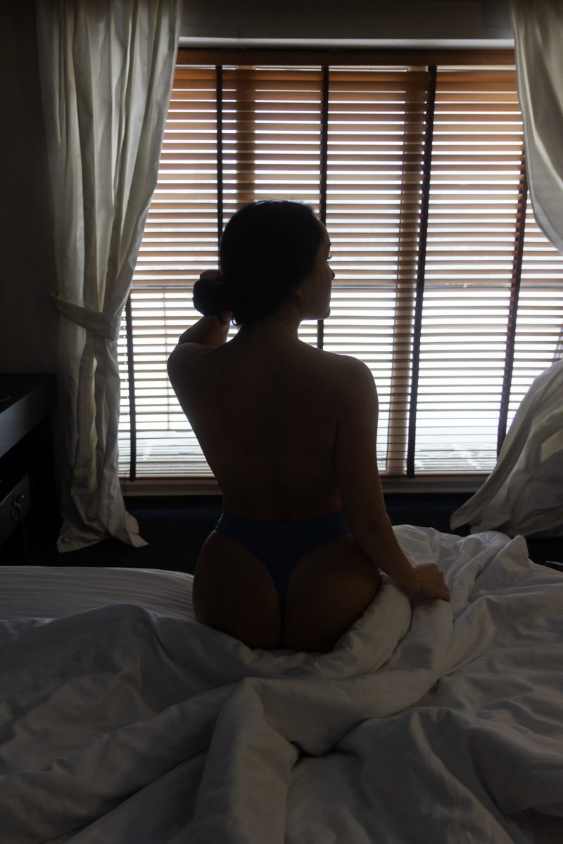 Rear View Of Woman Sitting On Bed