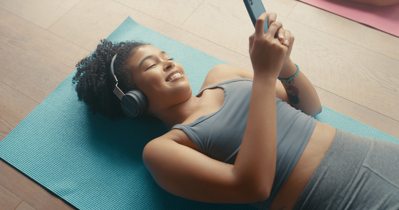 High angle shot of a young woman using a smartphone during a yoga class with her friends