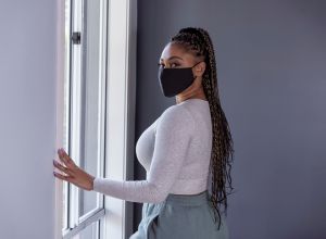 Woman in quarantine at home wearing cloth protective face mask