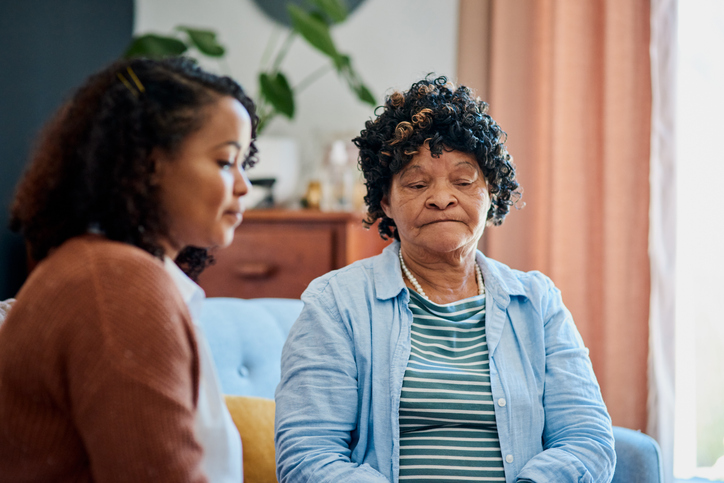 Shot of an elderly woman sitting with her daughter on the sofa at home and not talking