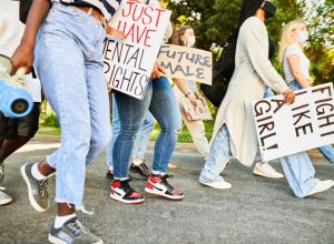 Young women walking with protest signs during a women's rights protest march