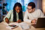 Diverse couple at home analysing their finance with documents.