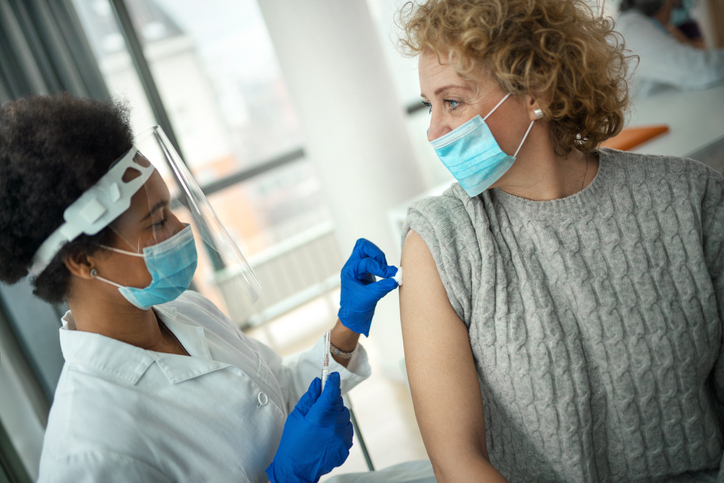 Black female doctor wearing a mask cares for female patient