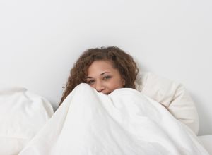 Woman hiding under bedcovers