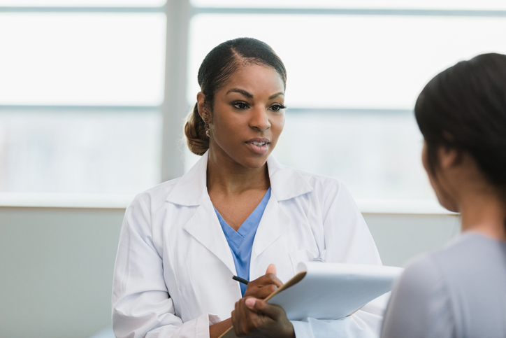 Serious female doctor documents patient symptoms