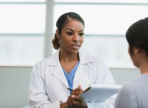 Serious female doctor documents patient symptoms