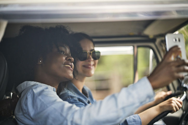 Female friends taking selfie while driving on road trip
