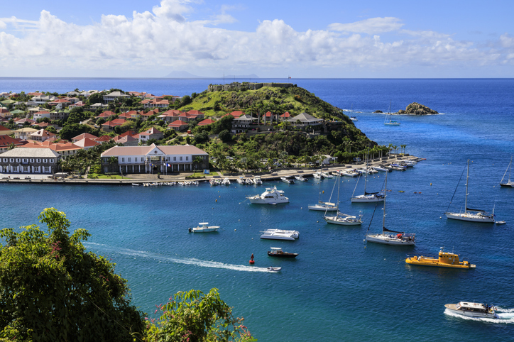 Elevated view over anchored yachts to Fort Oscar, passing small boats, Gustavia, St. Barthelemy (St. Barts) (St. Barth), West Indies, Caribbean, Central America