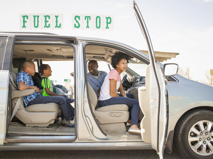 Road trip Family of 5 laughing in minivan at gas station 