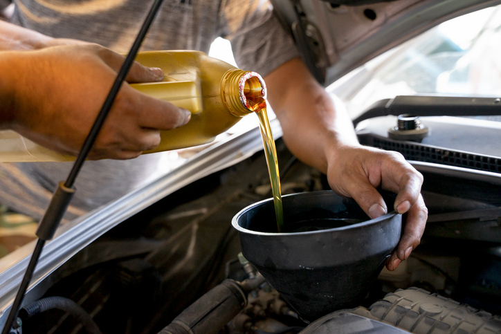 Mechanic man pouring engine oil to car engine