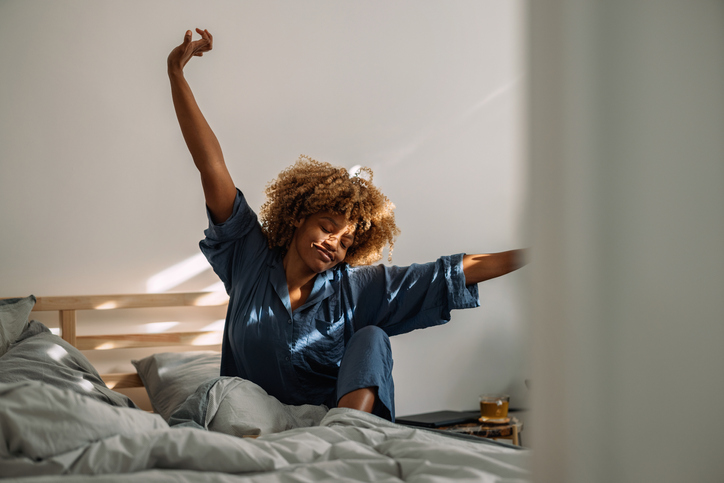 Beautiful Woman Waking Up and Stretching in Bed during daylight saving time