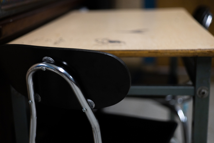 student desk with scribbles on surface & 2 chairs