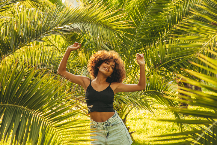 Pretty young afro woman among palm trees