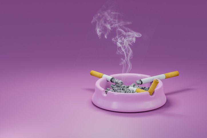 Smoking cigarettes left on porcelain ashtray full of ashes