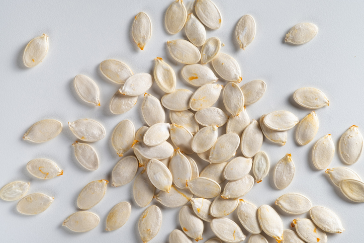 Raw pumpkin seeds on a white background, top view. The concept of vegetarianism, veganism and raw food. Vegetarian, vegan and raw food food and diet. Food background.