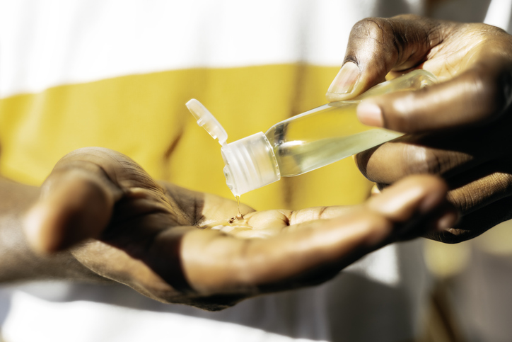 Black man is using sanitizing gel, hands close-up