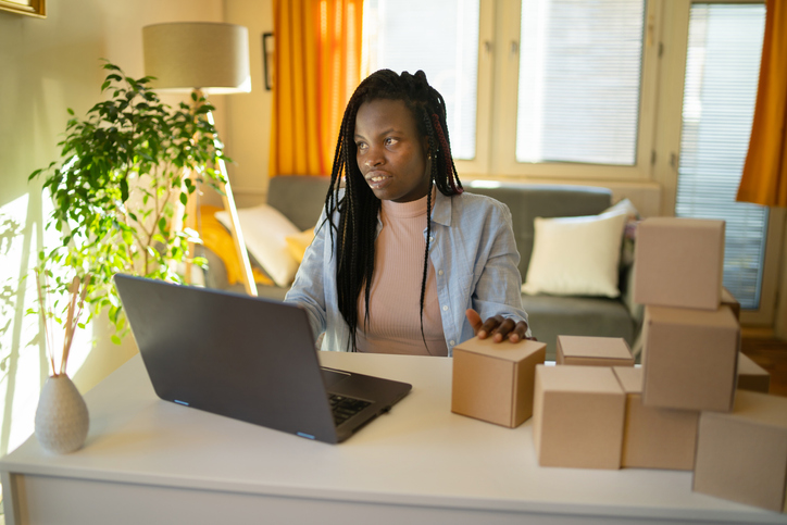 A female using a laptop in her living room for arranging selling of her products