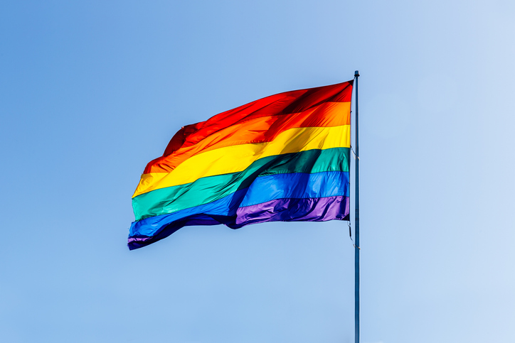 Rainbow LGBT flag waving in the wind against clear blue sky