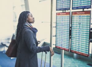Young woman at airport checking departures board.