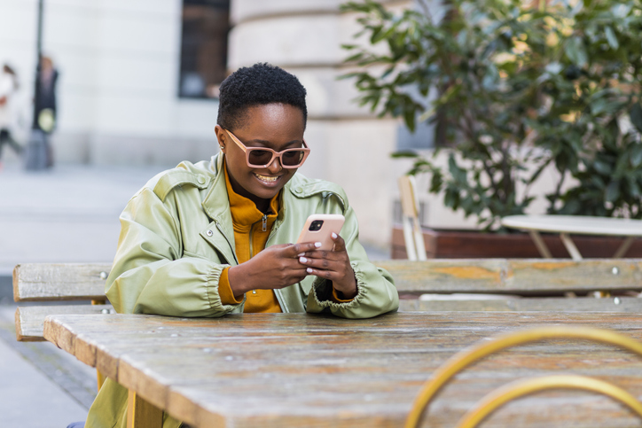 Beautiful black woman using her phone while sitting in a coffee shop.