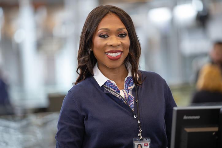 African American airline check in attendant smiles at camera.