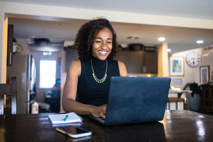 Beautiful Young Black Woman Working at Laptop at Dining Table