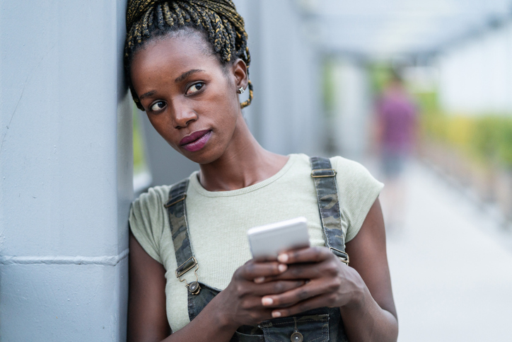 Close up of an young african woman with mobile phone, standing on a iron bridge depression