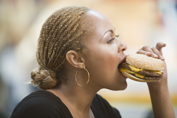 Mixed Race woman eating hamburger